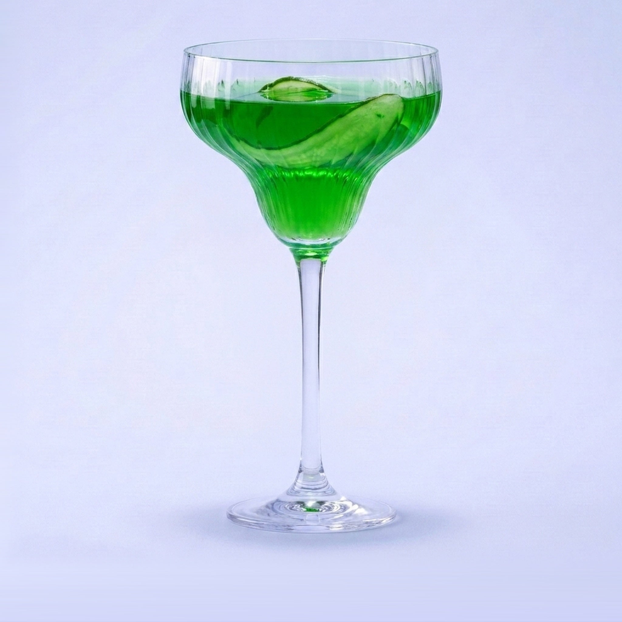 Royal Leerdam Bonheur Cocktails cocktailglas 30,5 cl gevuld met smaragdgroene cocktail en komkommerlint op pastelblauwe studioachtergrond